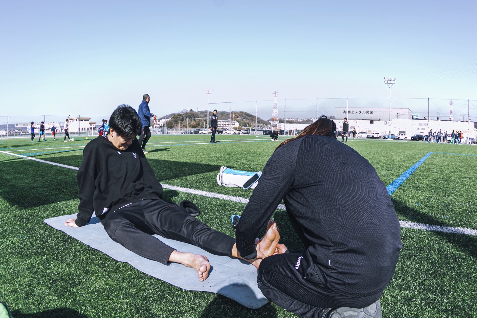 屋外スポーツ会場で選手の足を確認する代表