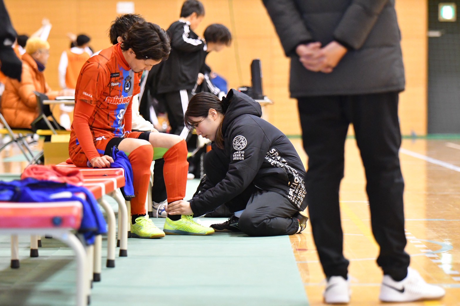 スポーツ現場で選手の足元を確認する代表